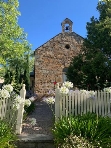 an old stone church with a white fence and flowers at Clare Valley Heritage Retreat in Clare