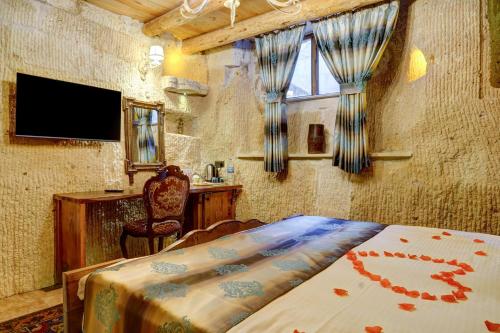 a bedroom with a bed and a desk and a television at Mizan Cave Cappadocia in Nevsehir