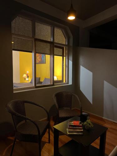 a living room with two chairs and a table and a window at Himtrek Stays,Mcleodganj in McLeod Ganj