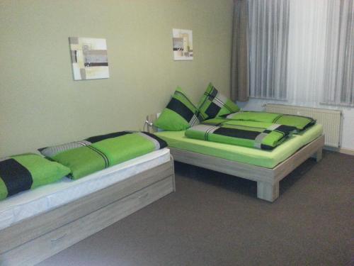 two beds in a room with green and black pillows at Ferienwohnung am Markt in Quedlinburg
