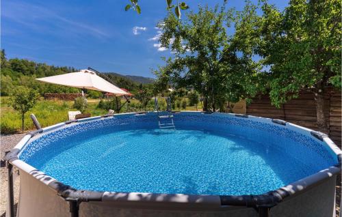 a large swimming pool with an umbrella and a table at 2 Bedroom Awesome Apartment In Fuzine in Fužine