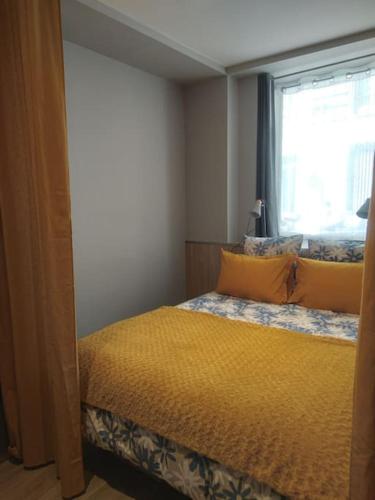 - une chambre avec un lit doté d'un couvre-lit jaune et d'une fenêtre dans l'établissement Appartement, à Paris