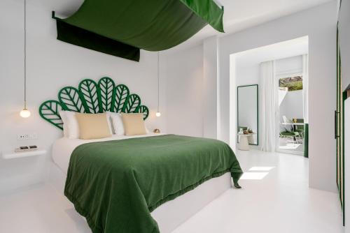 a bedroom with a green bed and white walls at Croco Mykonos in Tourlos
