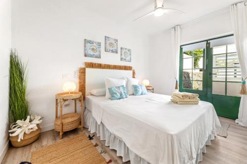 a bedroom with a bed with white sheets and blue pillows at Casa Yaiza in Puerto Calero
