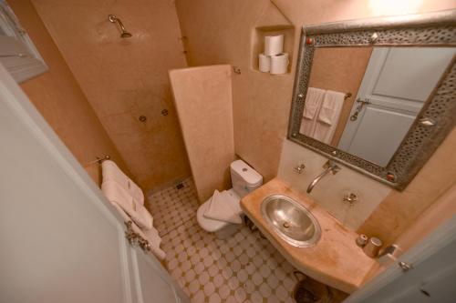 a bathroom with a sink and a toilet and a mirror at Maison d'hôtes Dar Farhana in Ouarzazate