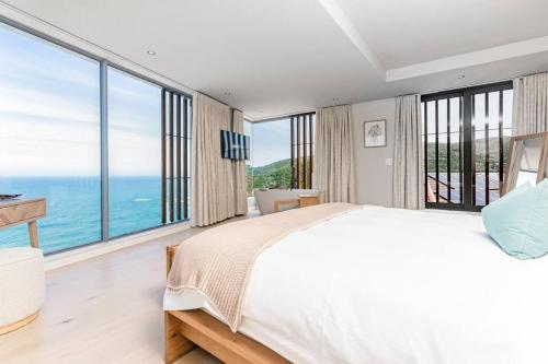 Un dormitorio con una cama grande y grandes ventanales. en Pure Emotions Luxury Villa, en Knysna