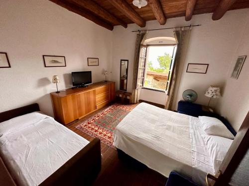 a bedroom with two beds and a tv and a window at Agriturismo Cervano in Toscolano Maderno