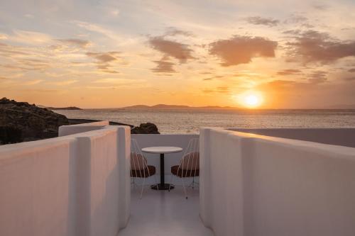 a balcony with a table and the ocean at sunset at Croco Mykonos in Tourlos