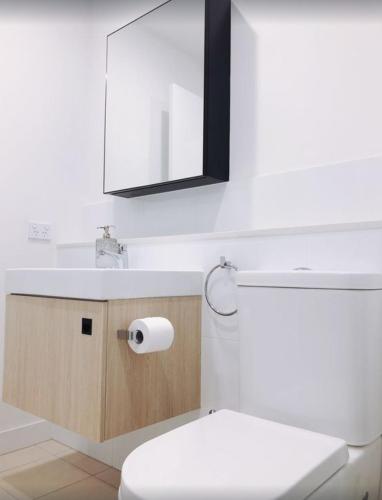 a bathroom with a toilet and a sink and a mirror at Modern 5-Guest Pool Retreat for Family & Business in Brisbane