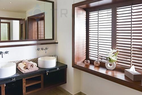 un bagno con specchio, lavandino e finestra di Spacious villa with 5-star hotel access - Belpe a Bel-Ombre