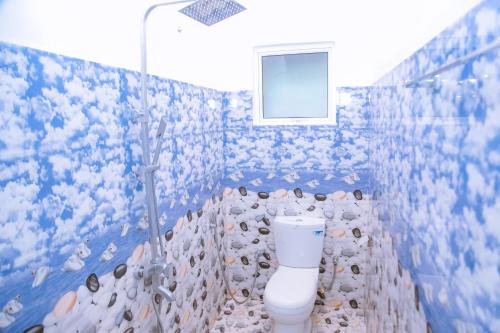 a bathroom with a toilet with a tree on the wall at Blue Sky in Mirissa