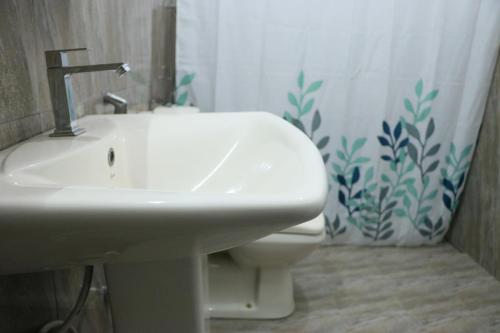 a bathroom with a sink and a toilet and a shower curtain at Sheru Guest in Matara