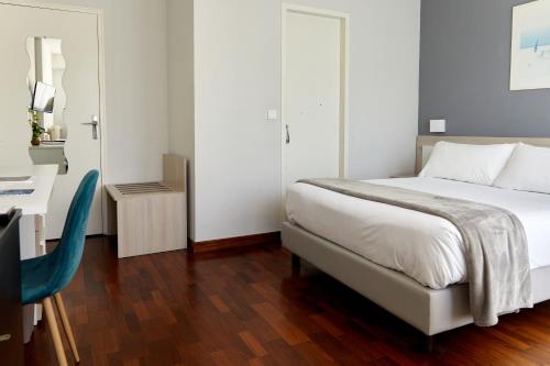 a bedroom with a bed and a desk and a chair at Hôtel Alexandra in Roquebrune-Cap-Martin