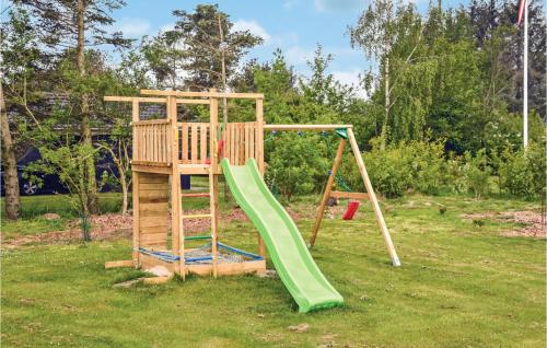 a playground with a green slide in a yard at Holiday Home Hindbærvangen Oksbøl V in Oksbøl