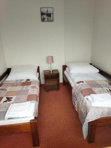two beds in a room with a lamp on a table at Dom Wypoczynkowy Bajka in Krynica Zdrój