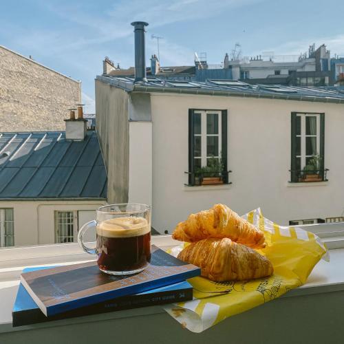 - une tasse de café et des croissants sur une table dans l'établissement MONTMARTRE ROMANTIC, Bed & Breakfast - Paris, à Paris