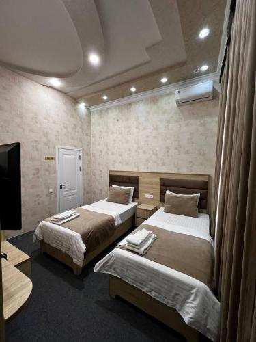 a hotel room with two beds and a tv at Shosh Palace in Tashkent