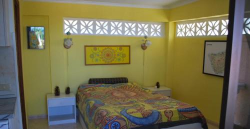 a yellow bedroom with a bed and two windows at Confortable Estudio con Terraza, Piscina y Bbq in Icod de los Vinos