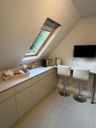 a kitchen with a counter with two chairs and a window at Idyllic rural retreat in Plumpton Green