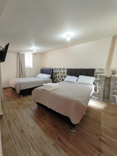 a bedroom with two beds and a stone wall at Centro Cusco Inti in Cusco