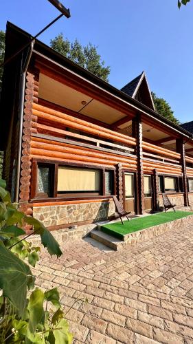 a log cabin with a green lawn in front of it at Chalet Vedmezhe in Polyana