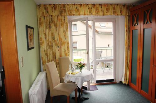 a room with a table and chairs and a balcony at Pension Villa Irene in Kurort Gohrisch