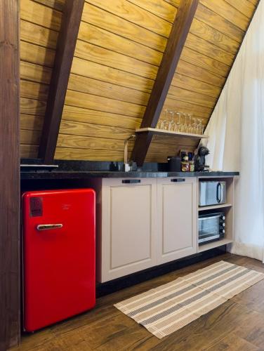 a red refrigerator in a kitchen with a wooden ceiling at Pousada Duas Marias in Nova Veneza