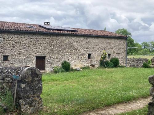 an old stone building with a grass field next to it at Cosy cottage in rural paradise in Saint-Aubin-de-Branne