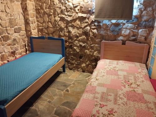 two beds in a room with a stone wall at Το πέτρινο 2 in Agia Marina Mikrolimanou