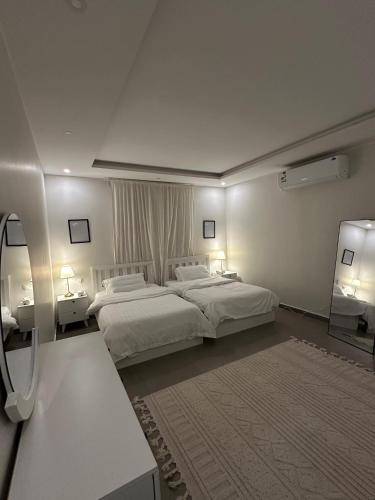 a bedroom with two beds and two tables and two lamps at Modern cozy apartment in Riyadh