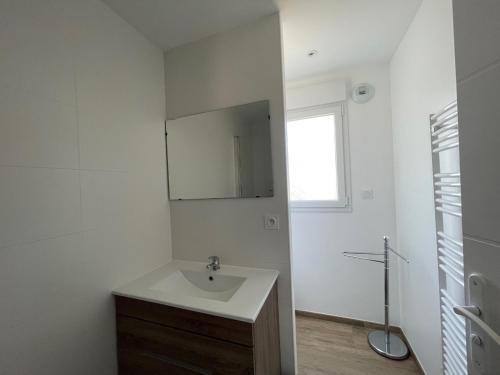 une salle de bain blanche avec un lavabo et un miroir dans l'établissement Les Aigrettes, à Sarzeau