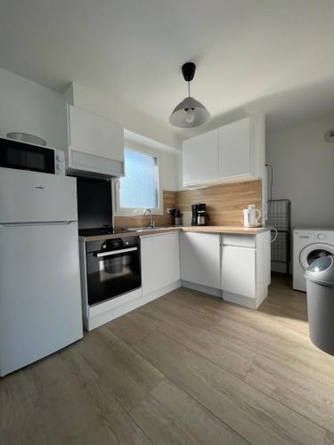 une cuisine avec des armoires blanches et un four à plaques de cuisson dans l'établissement Les Aigrettes, à Sarzeau