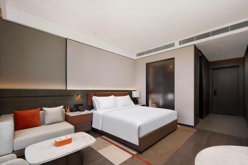 a hotel room with a bed and a couch at Doubletree By Hilton Kaifeng in Kaifeng