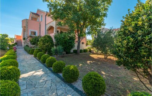 a garden in front of a pink house with bushes at Four-Bedroom Holiday Home In Miranje in Miranje