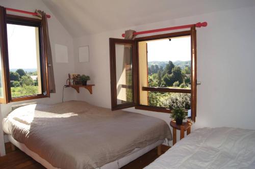 une chambre avec deux lits et deux fenêtres dans l'établissement Le monteil, à Calviac