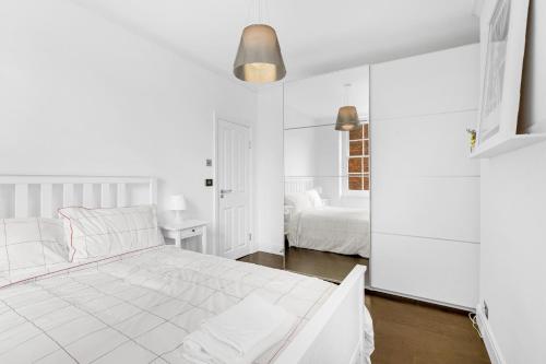 a white bedroom with a large white bed and a desk at The Bronwen in London