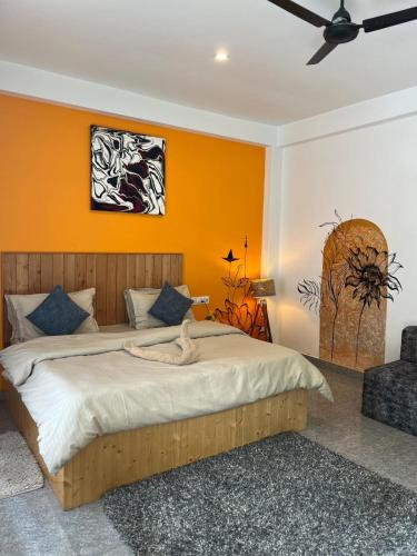 a bedroom with a large bed with an orange wall at Himtrek Stay Kasol in Kasol