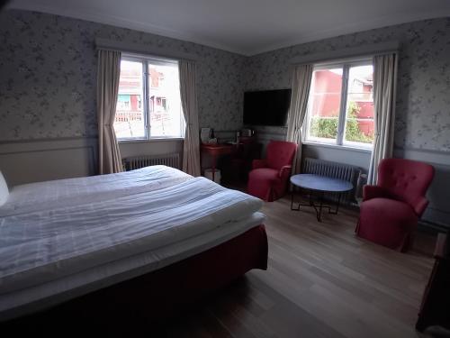 a bedroom with a bed and two chairs and a television at Tällbergsgårdens Hotell in Tällberg