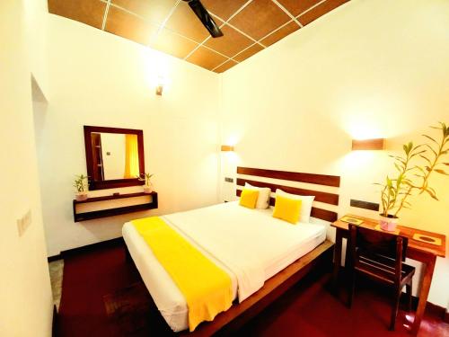 a bedroom with a bed and a desk and a mirror at Coco Garden Villas 4 in Hikkaduwa