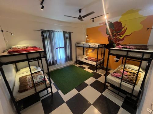 a room with four bunk beds and a checkered floor at Himtrek Stay Kasol in Kasol