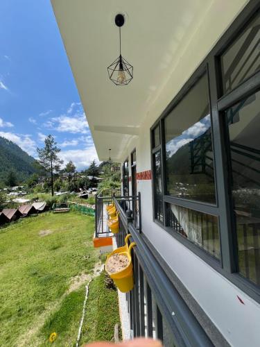 a balcony of a house with a view of a field at Himtrek Stay Kasol in Kasol
