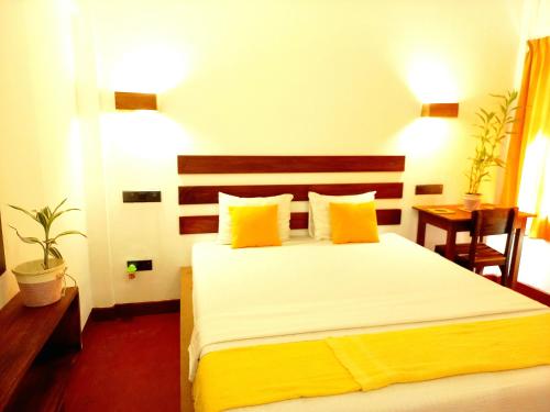a bedroom with a large bed with yellow pillows at Coco Garden Villas 4 in Hikkaduwa