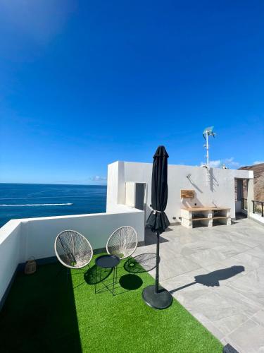 a patio with two chairs and an umbrella at Ático El Mirador in Sardina