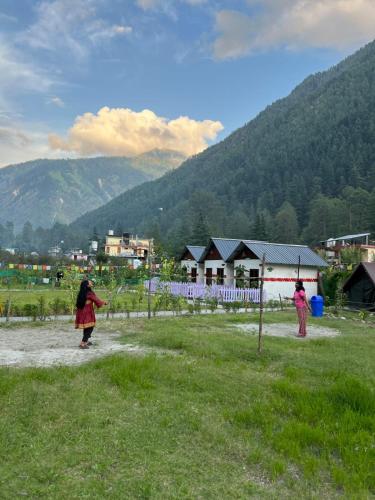 two people are flying a kite in a field at Himtrek Stay Kasol in Kasol