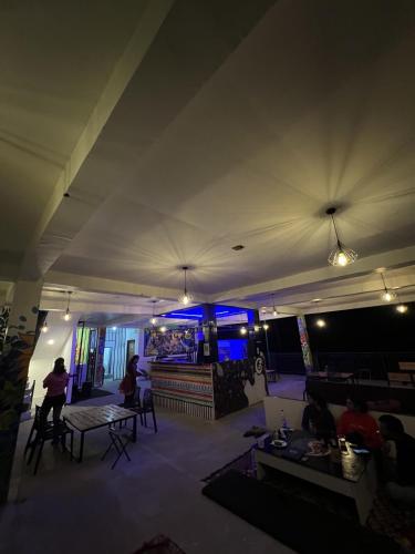 a room with people sitting at tables and a stage at Himtrek Stay Kasol in Kasol