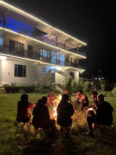 a group of people sitting around a fire at night at Himtrek Stay Kasol in Kasol
