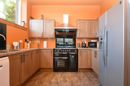 a kitchen with wooden cabinets and a black oven at Taigh na Mara in Kames