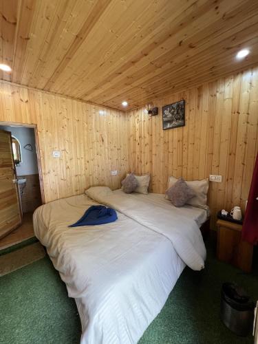 two beds in a room with wooden walls at Himtrek Stay Kasol in Kasol