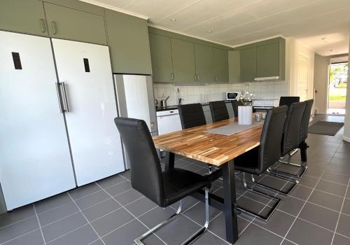 a kitchen with a wooden table and black chairs at Saxnäs Ferieboende Loke in Färjestaden