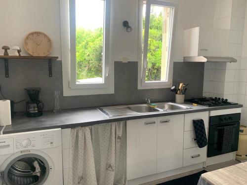 une cuisine avec un évier et une machine à laver dans l'établissement Appartement, à Gourdon